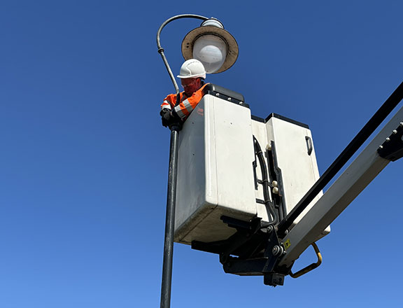 employee in ascended crane fixing a street lamp